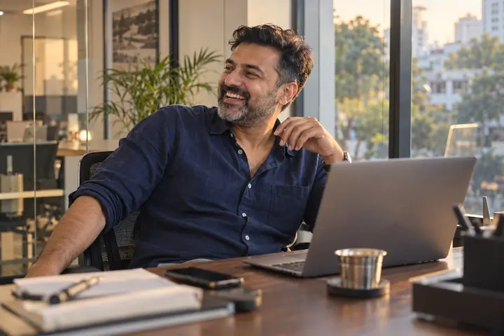 Property founder laughing at his desk in Bengaluru