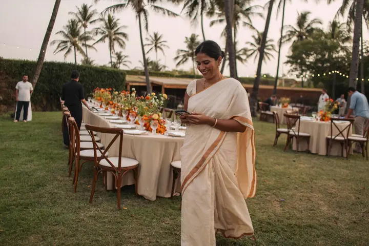 Venue manager in a Kerala saree checking bookings as a wedding lawn is set up
